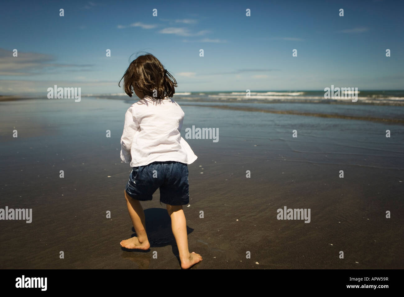 Fille court avec du sable mouillé à la plage de 4 ans Banque D'Images