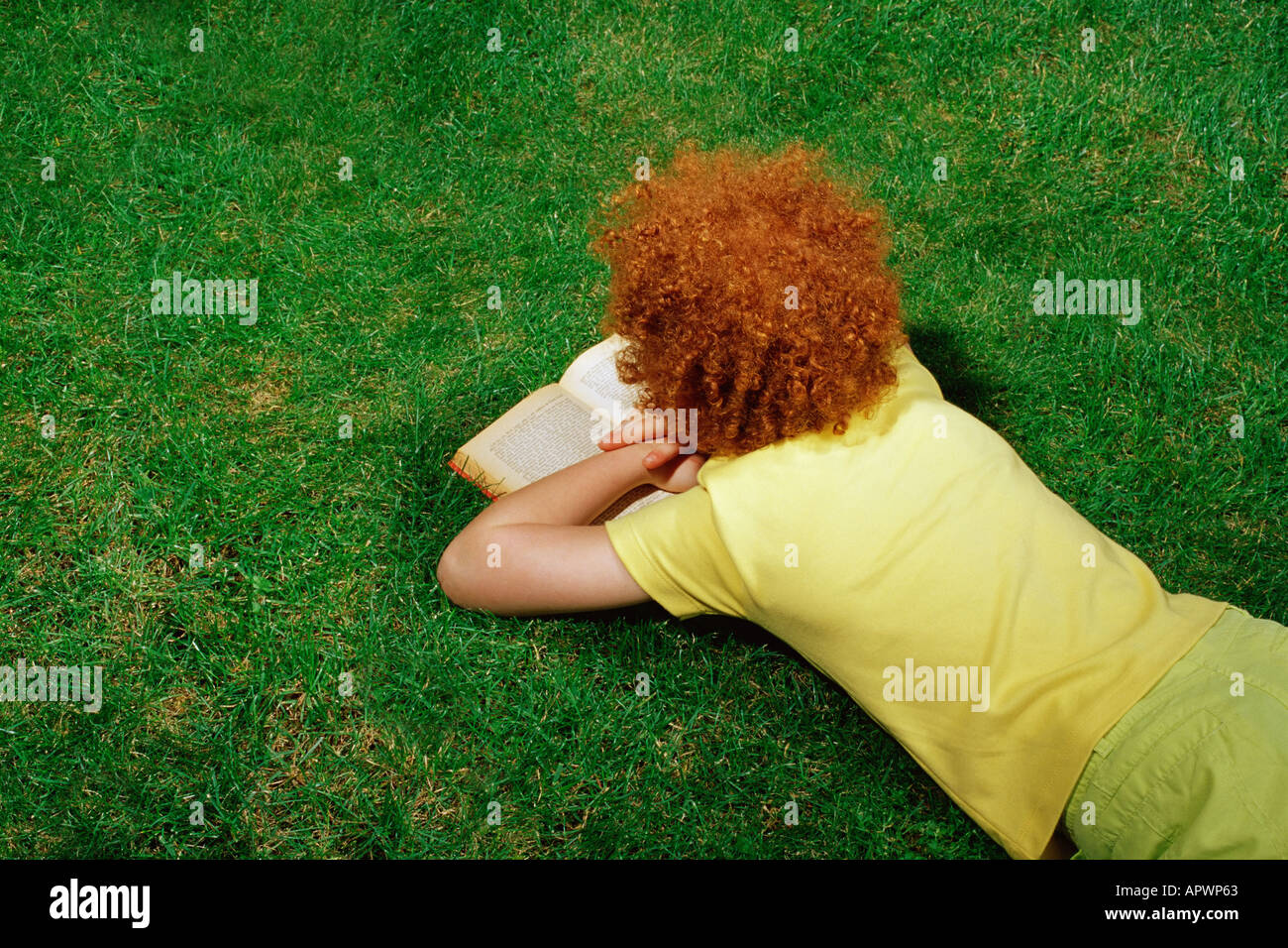 Girl lying on the grass reading a book Banque D'Images