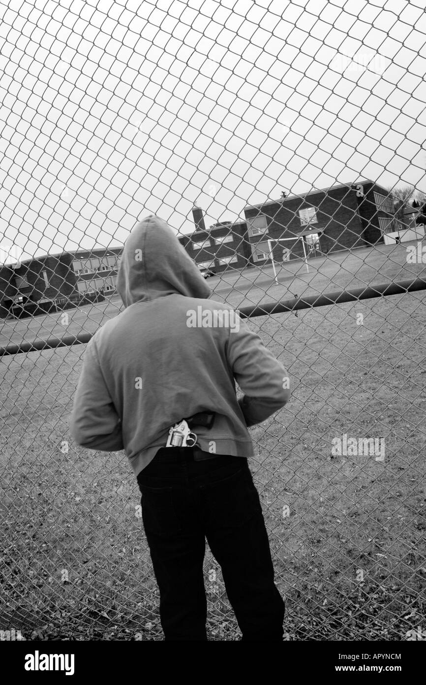 Homme seul hoodie et port holding gun en face de l'école secondaire Banque D'Images