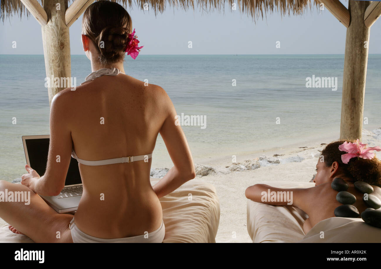 Les jeunes femmes qui reçoivent des massages à la plage et à l'aide d'ordinateur portable. Banque D'Images