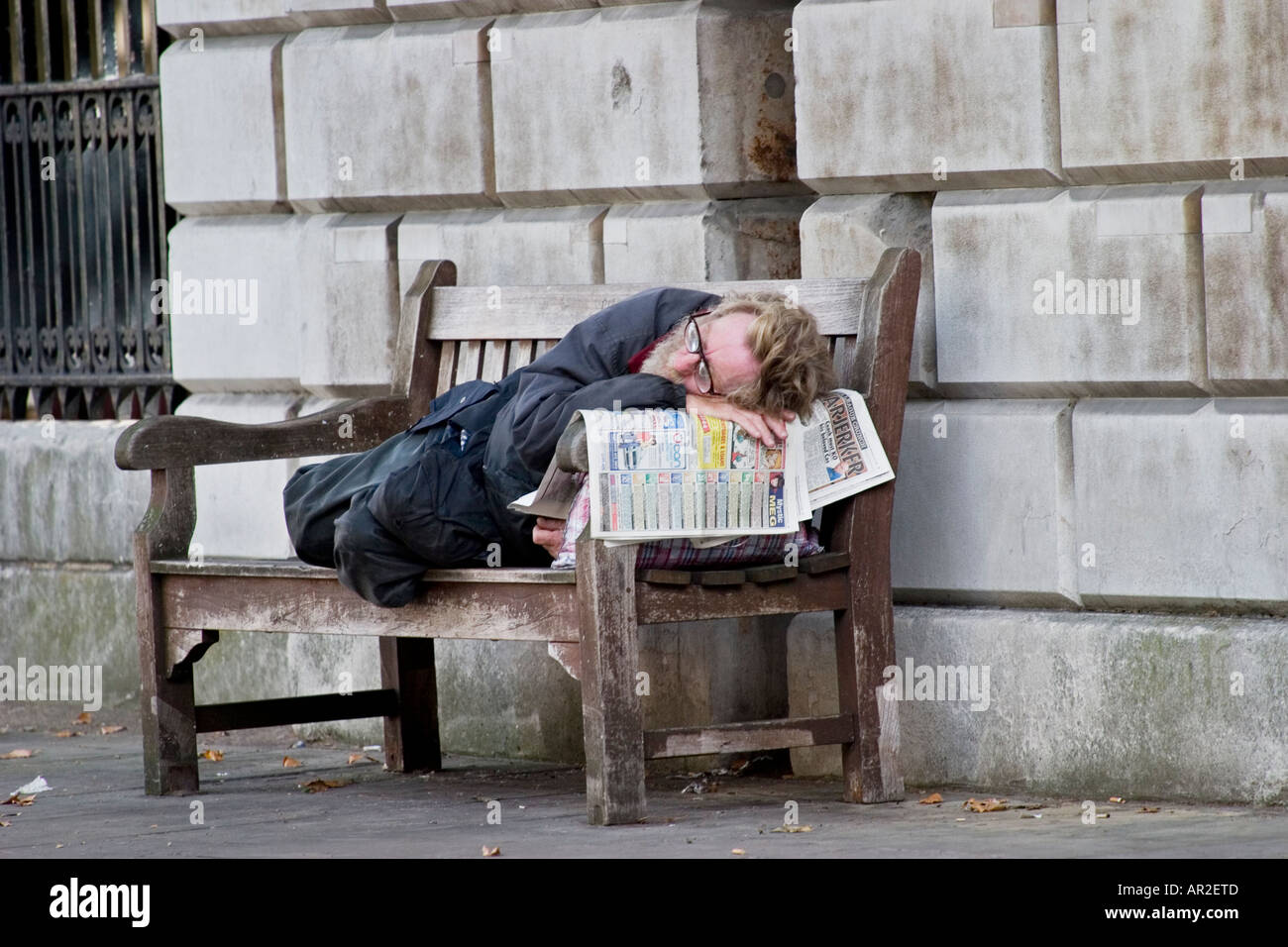 Sans-abri dort sur banc à l'extérieur de St Bartholomews hospital London Banque D'Images