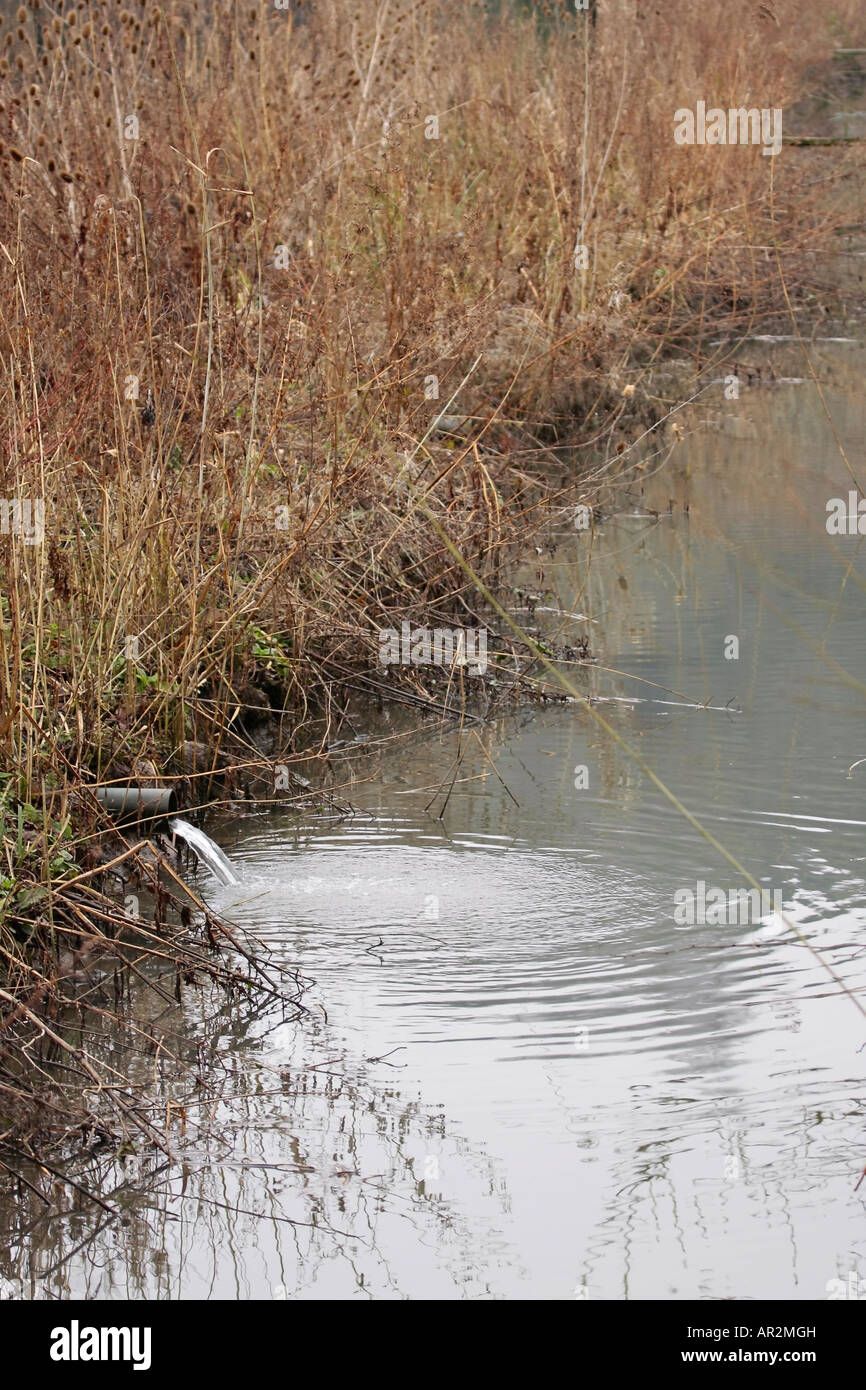 L'eau s'écoulant du tuyau dans la rivière en hiver, Sussex, Angleterre, Royaume-Uni Banque D'Images