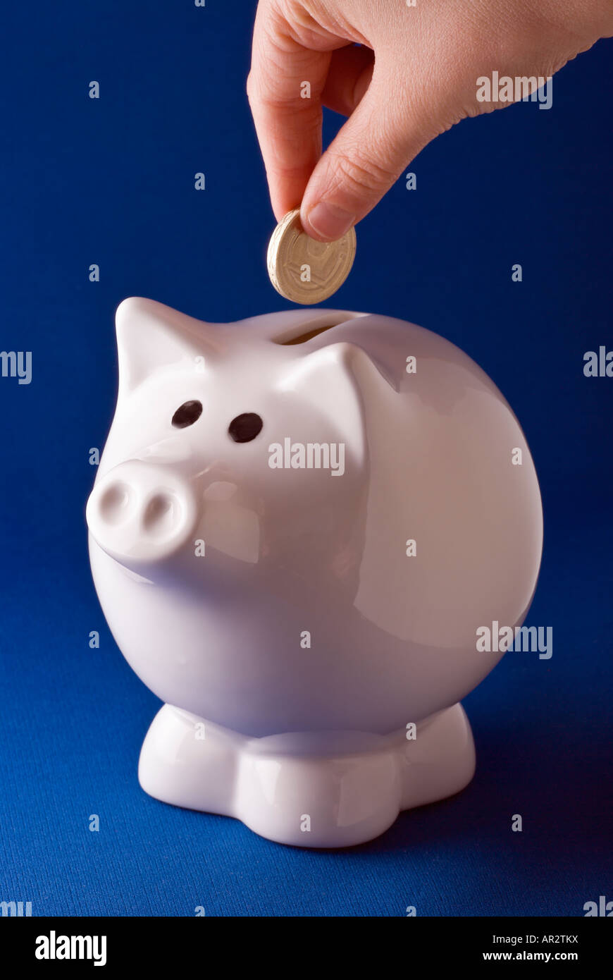 Une main mise de l'argent dans une tirelire. Banque D'Images