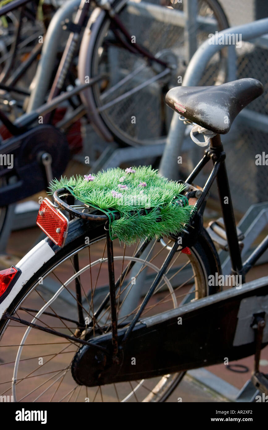 AMSTERDAM HOLLAND BIKE stationné dans le parc à vélos de plusieurs étages avec de l'HERBE ET DES FLEURS EN PLASTIQUE À L'ARRIÈRE TRANSPORTEUR Banque D'Images