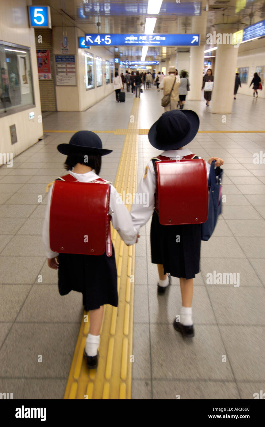 Deux jeunes écolières japonaise marcher dans une gare ferroviaire au Japon Banque D'Images