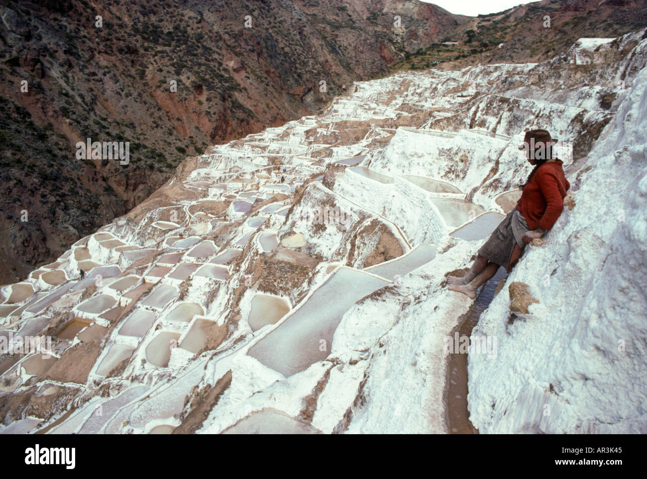 C'est un travailleur de travailler le sel terrasses à Salinas près de Cusco au Pérou Banque D'Images