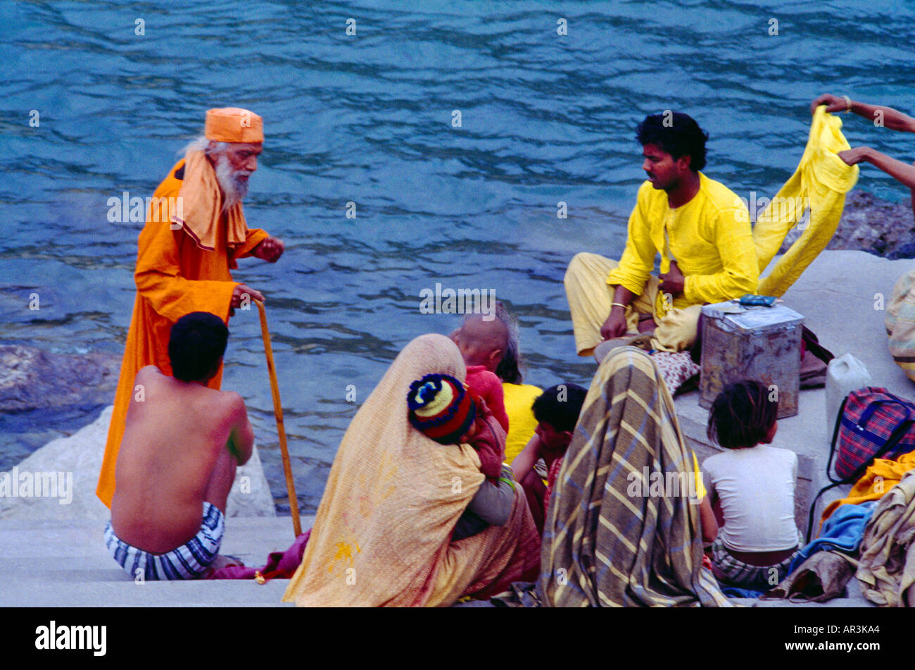 Rishikesh Inde Sadhu avec un bâton de marche parle à une famille sur les banques de Ganges Banque D'Images