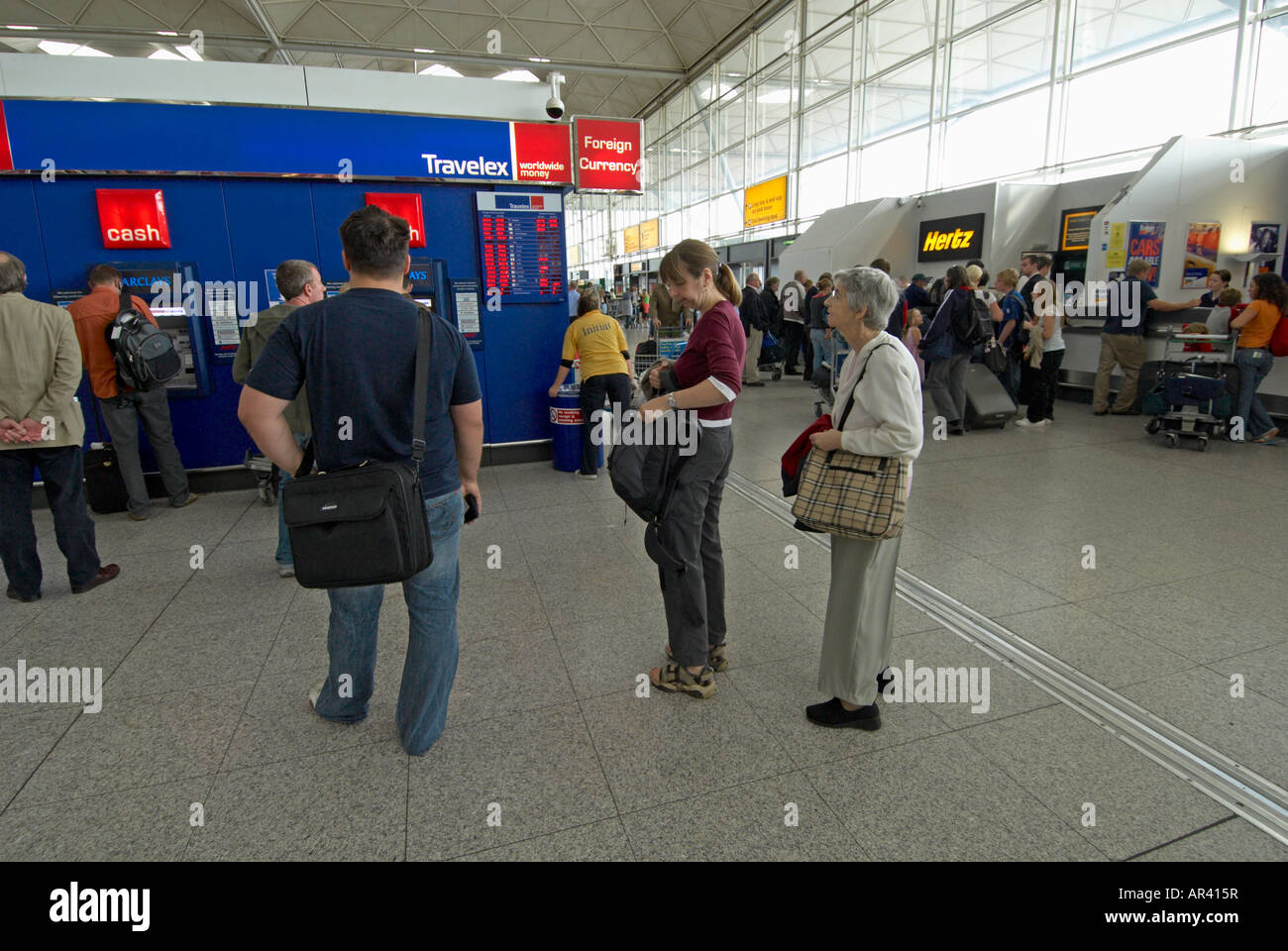 Les passagers (mère-fille) à l'intérieur de l'aéroport de Stansted en attente de l'argent au bureau de change Travelex Banque D'Images