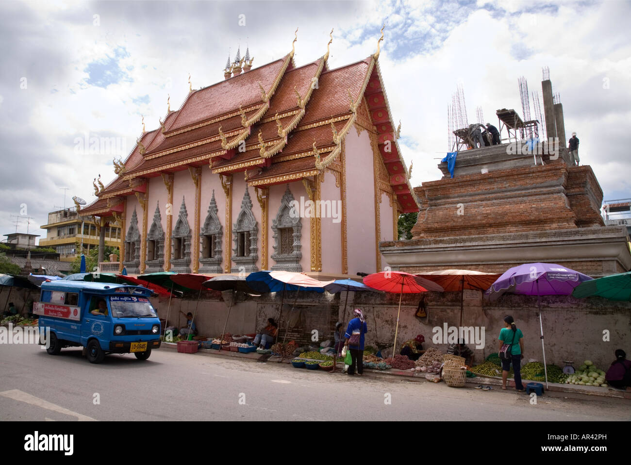 Le côté de Wat Munguan à Chiang Rai montrant les travaux de construction et les étals du marché de rue vendant des fruits. La Thaïlande. Banque D'Images