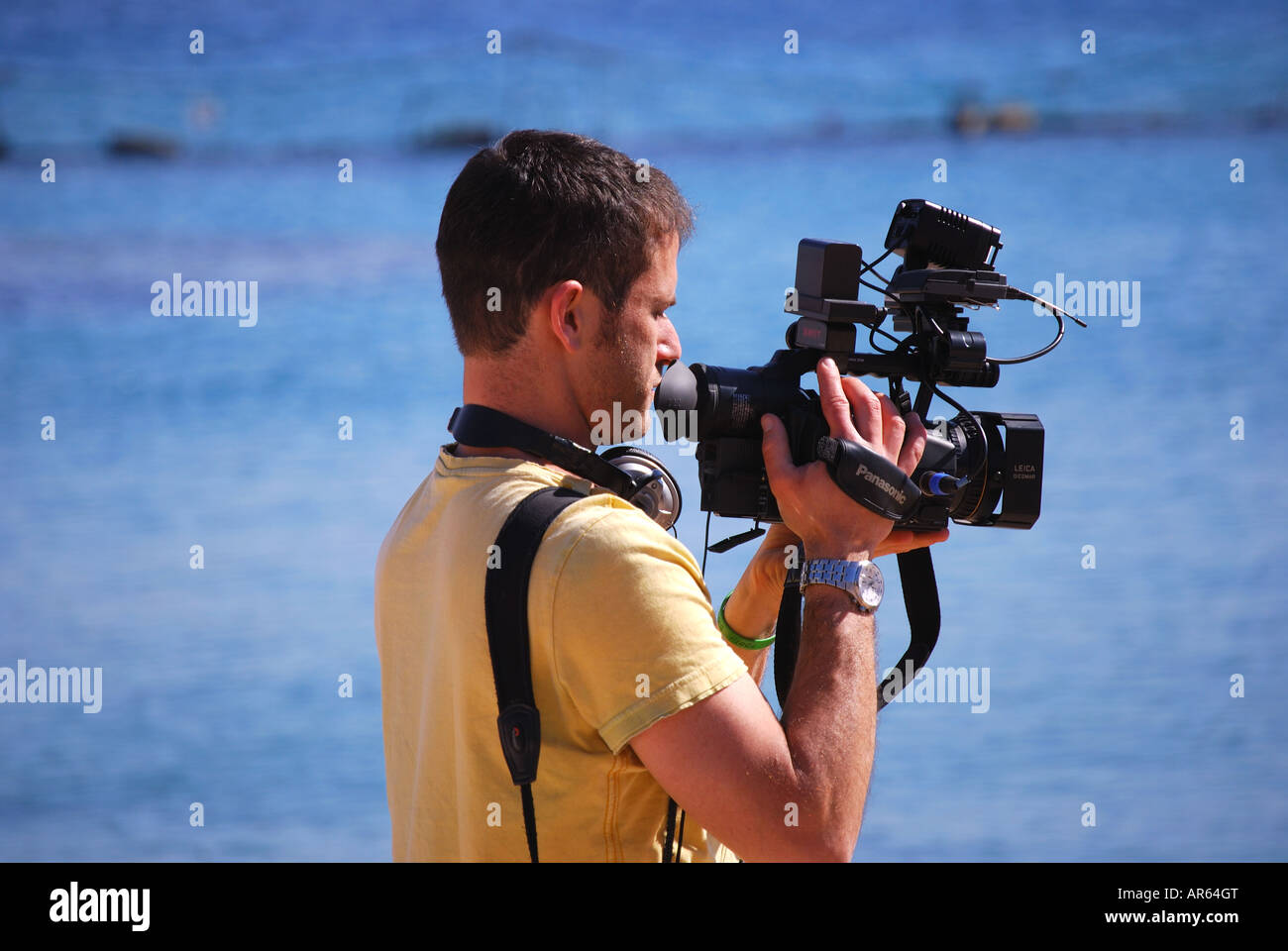 Homme filmant photo modèle sur la plage, Dolphin Reef, Eilat, Israël Banque D'Images