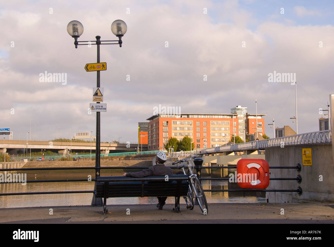 Lagan Weir homme est assis sur un banc au bord de la rivière Lagan n Belfast irlande du nord système de contrôle du niveau de l'eau fond de ciel bleu b s Banque D'Images