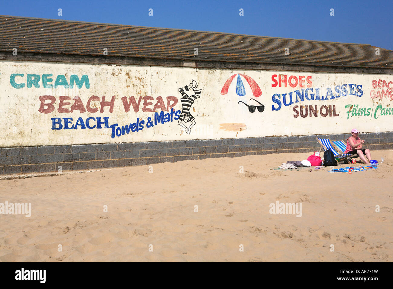 Femme assise sur un transat, appréciant le soleil d'Camber Sands Beach Kent Banque D'Images