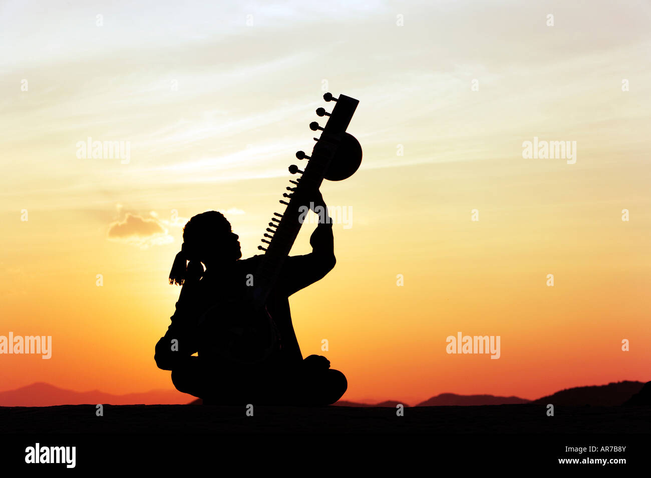 L'homme indien jouant un sitar sur rock au coucher du soleil. L'Inde Banque D'Images