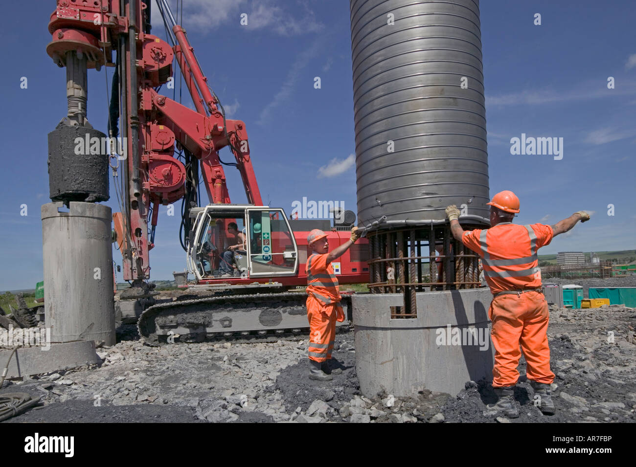 Installer les travailleurs en cage acier renforcé pile excavé. Dans l'arrière-plan, un énorme butin de piling rig soulève une autre pile Banque D'Images