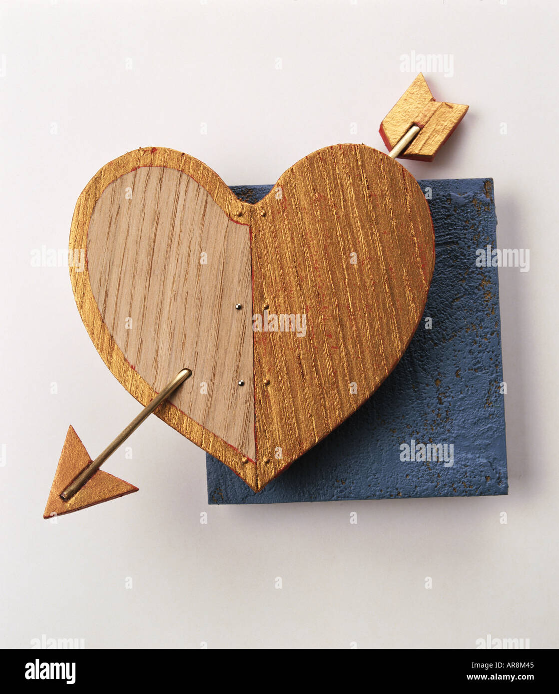 Coeur d'amour avec la flèche en bois par perçage, fond bleu. Banque D'Images
