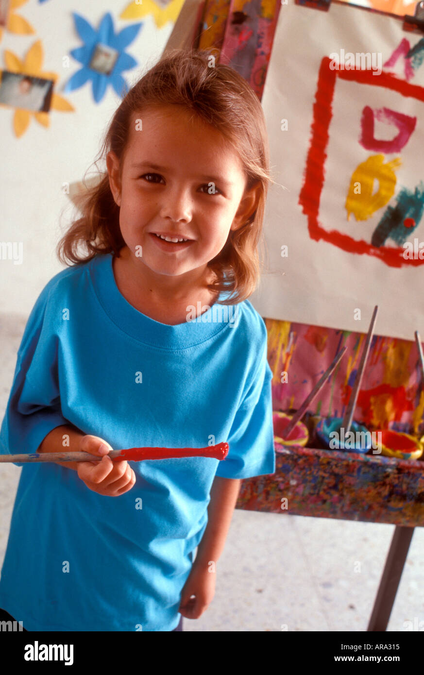 Classe d'art fille heureux infantile CHEVALET CHEVALET Caucasian girl de 4 à 5 ans maternelle holding paintbrush dans la classe d'art Banque D'Images