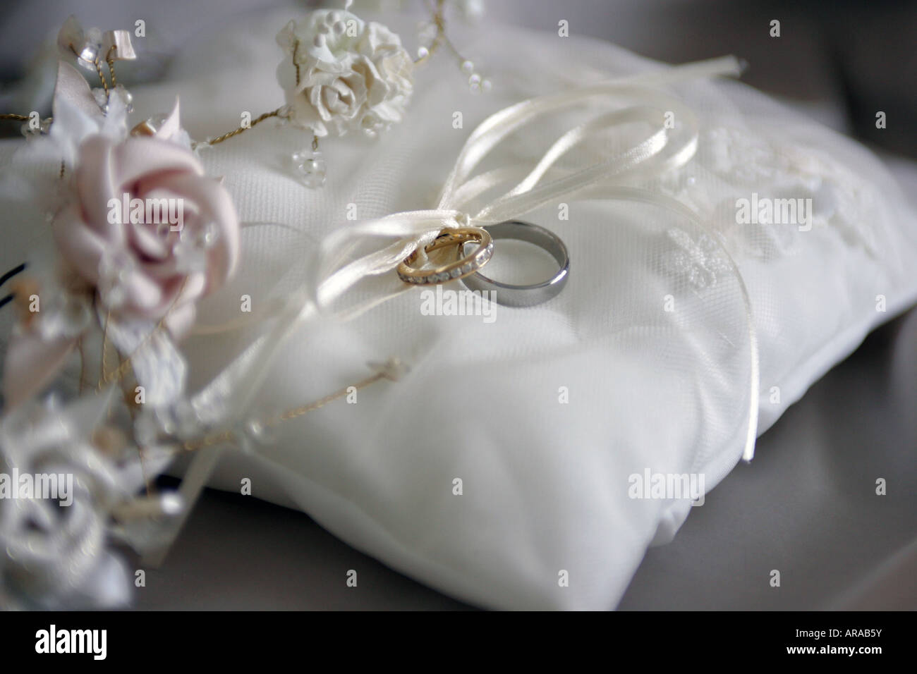 Mariée et le marié mariage sur blanc coussin avec bouquet de fleurs Banque D'Images