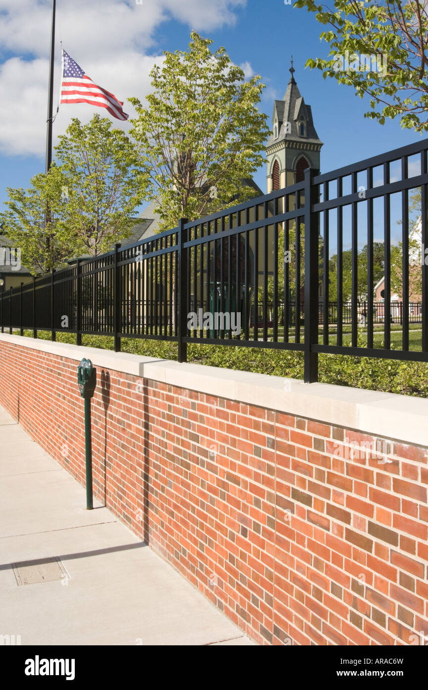 Scène de rue américaine avec un parc clôturé dans une petite ville. Un drapeau est battant, demi-personnel, sous le soleil, les trottoirs, la rue principale. Banque D'Images