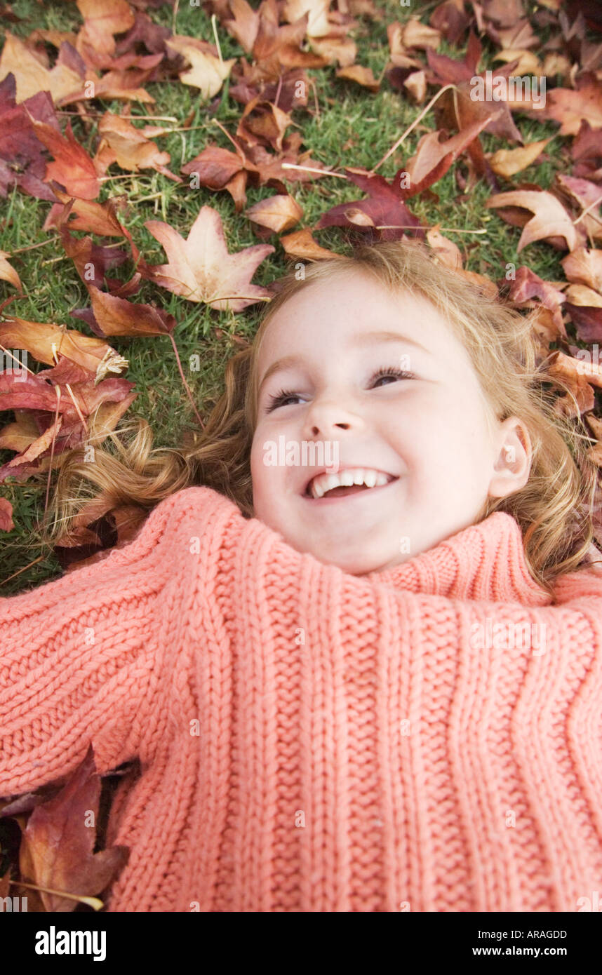 Happy young girl (5-7 ans) parmi les feuilles mortes, Close up Banque D'Images