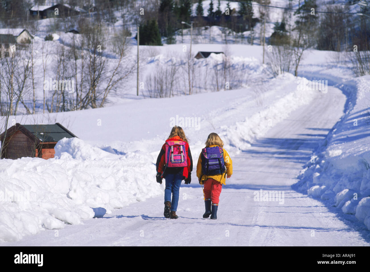 Deux enfants de l'école avec des sacs à dos sur les routes de campagne en hiver en Scandinavie Banque D'Images