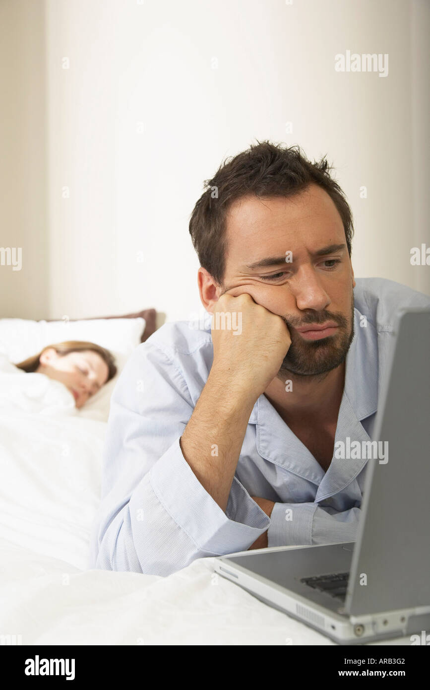 Man Using Laptop in Bed Banque D'Images