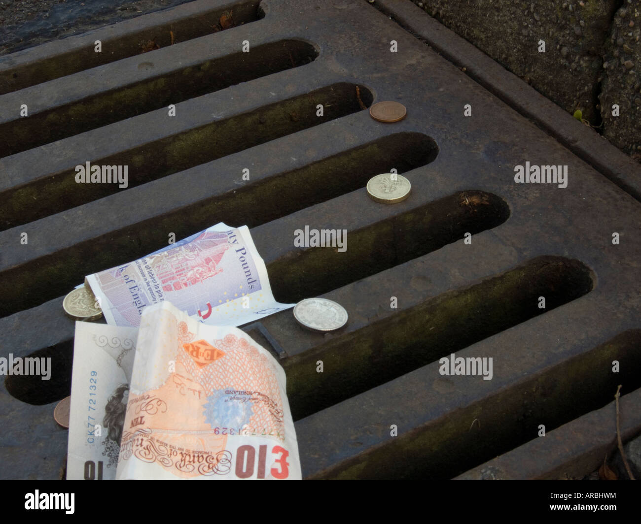 Image conceptuelle de billets de banque et pièces de monnaie sur une vidange côté route Banque D'Images