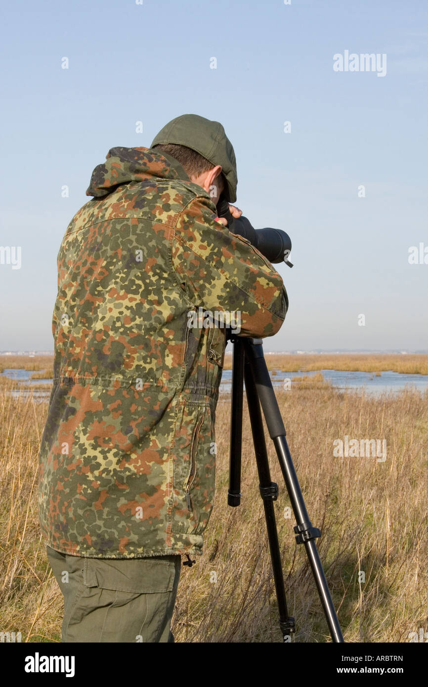 Observateur d'oiseaux côtiers, habillé en vert, à l'aide de la portée de cacher à Sandside, Marshside la réserve RSPB, Southport, Merseyside, Royaume-Uni Banque D'Images