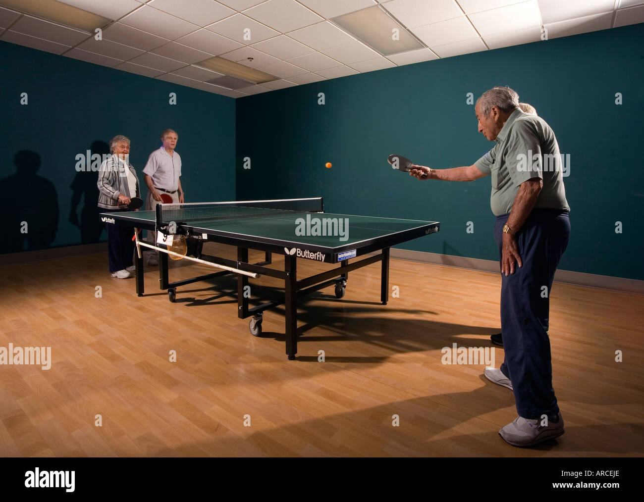 Les hommes âgés et les femmes âgées de leur 70 s pour leur 90 s jouer ping pong Banque D'Images