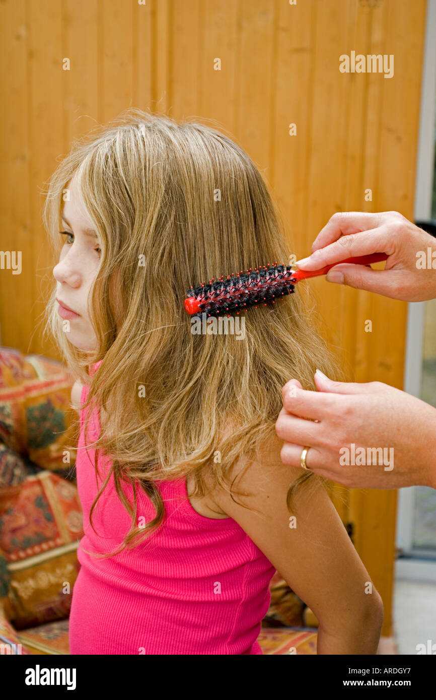 Brossage des cheveux emmêlés mère de neuf ans, fille, UK Banque D'Images