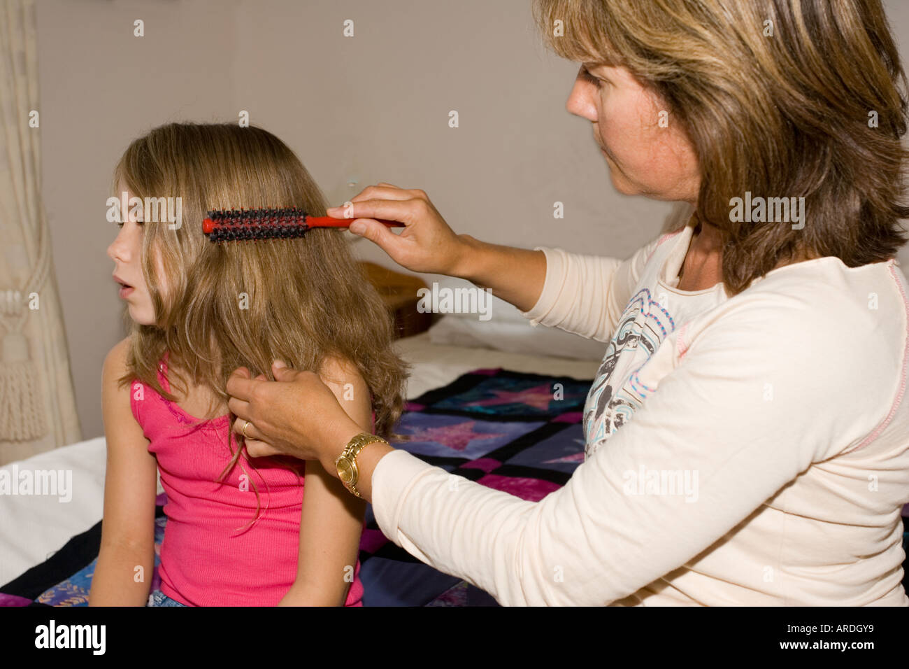 Brossage des cheveux emmêlés mère de neuf ans, fille, UK Banque D'Images