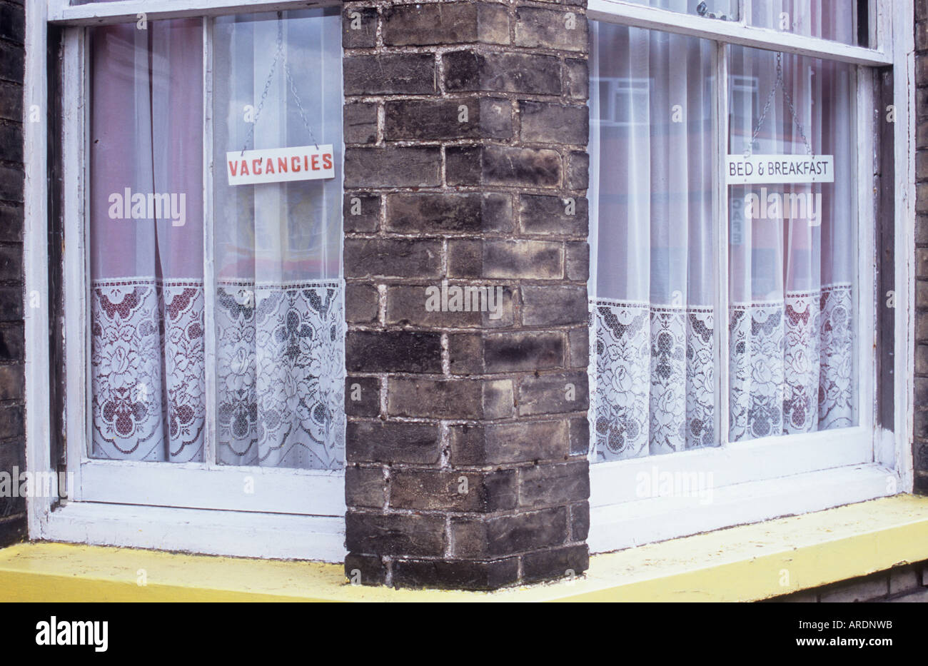 Close up de fenêtres à guillotine avec briques sales sales contenant des signes et des rideaux net Postes vacants et lit et petit déjeuner Banque D'Images