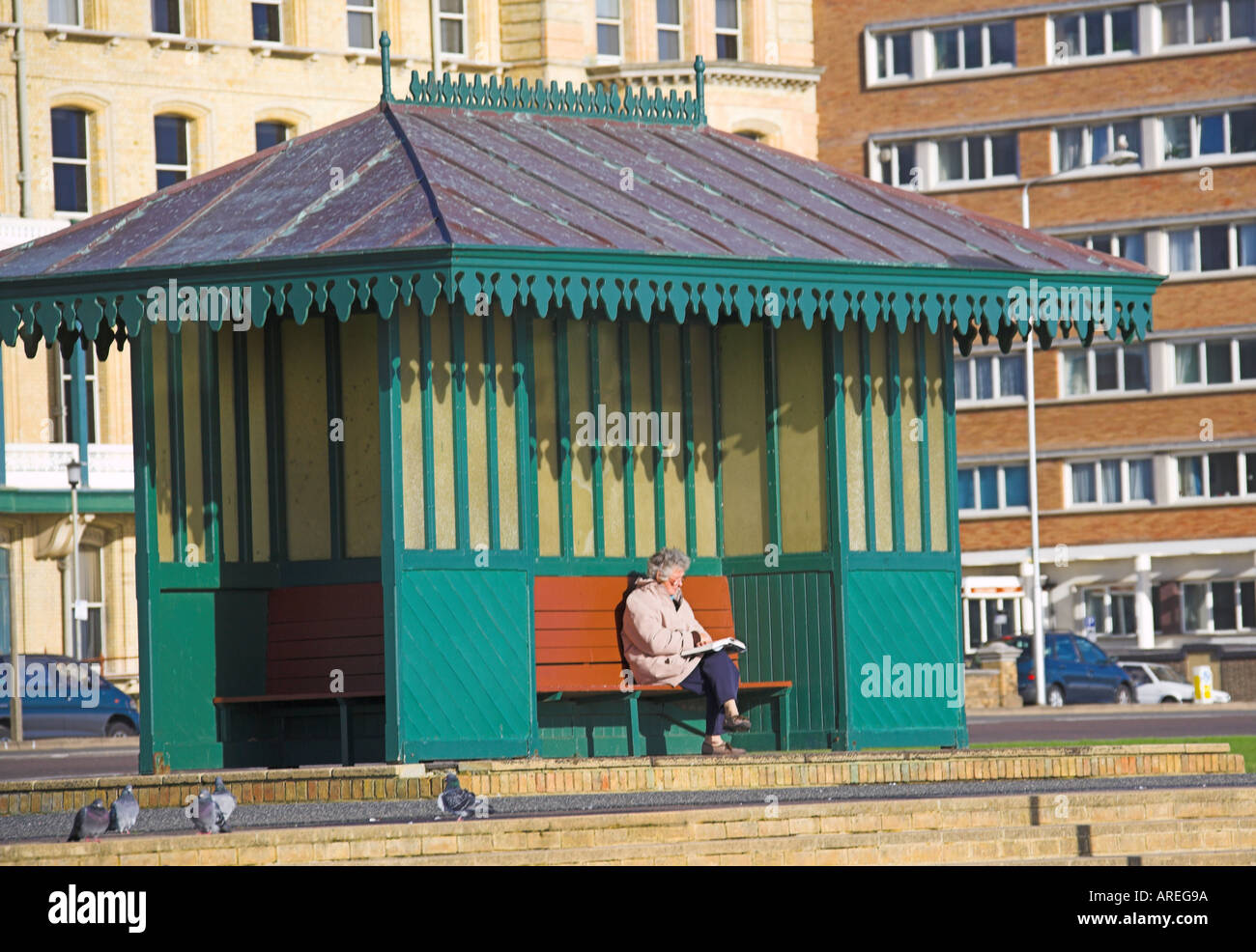 Femme assise dans un abri du vent, promenade Sussex, Brighton Banque D'Images