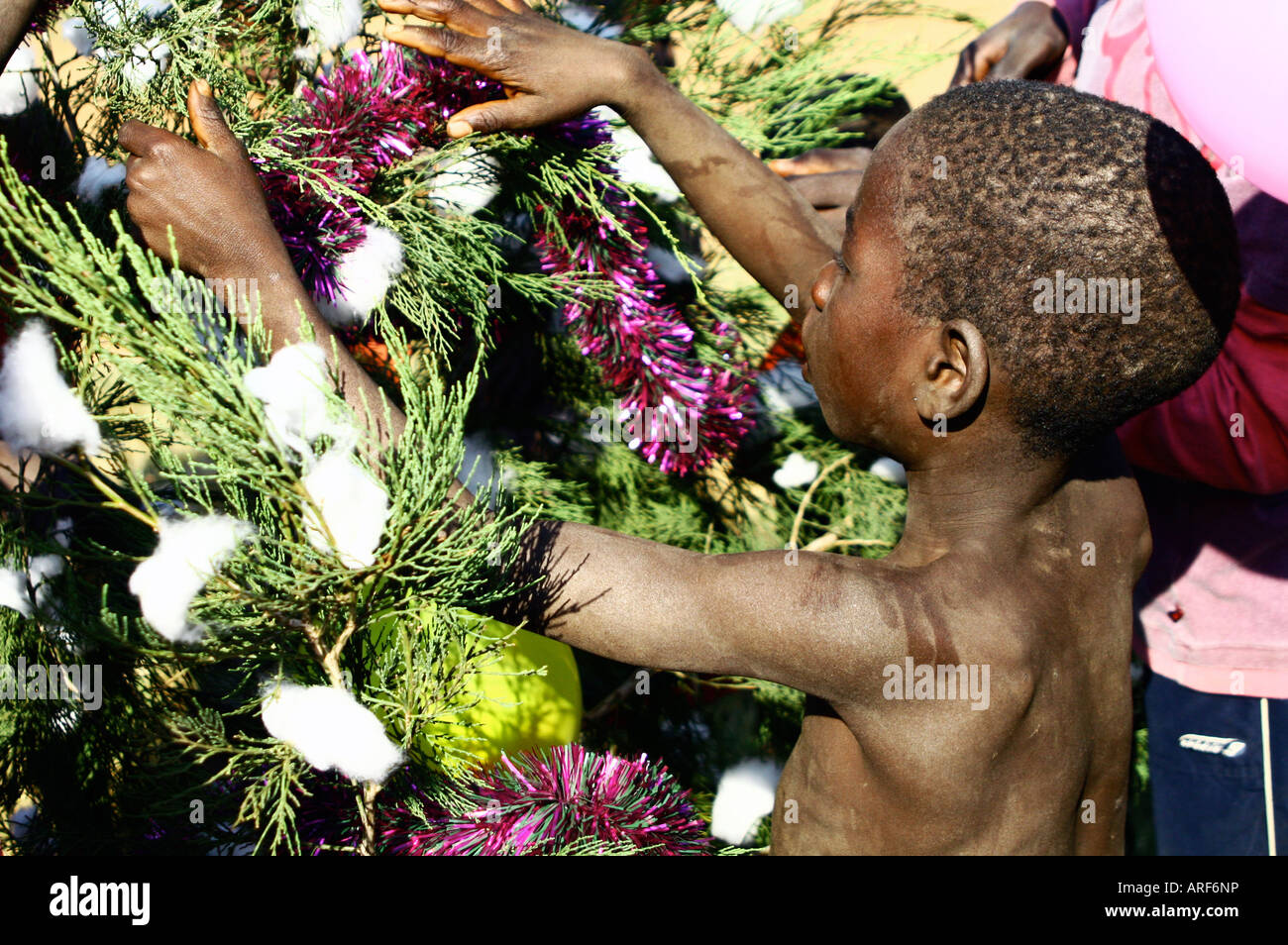 Un jeune garçon décore un arbre de Noël dans le camp de personnes déplacées Atiak.. Le nord de l'Ouganda. Banque D'Images