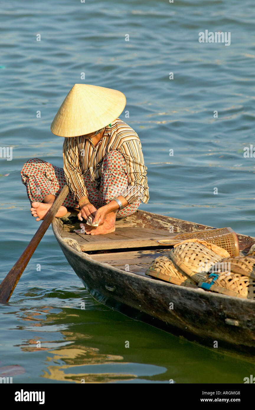 Une femme compter son argent à la fin de la journée près du marché aux poissons à Hoi An, au Vietnam. Banque D'Images