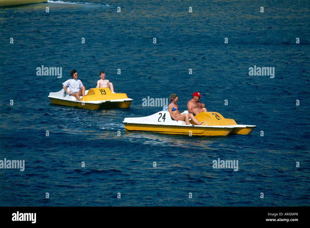 Les familles apprécieront le plaisir de pousser leurs pédalos numérotés jaune et blanc à travers les eaux calmes de la baie abritée de Puerto Rico Banque D'Images