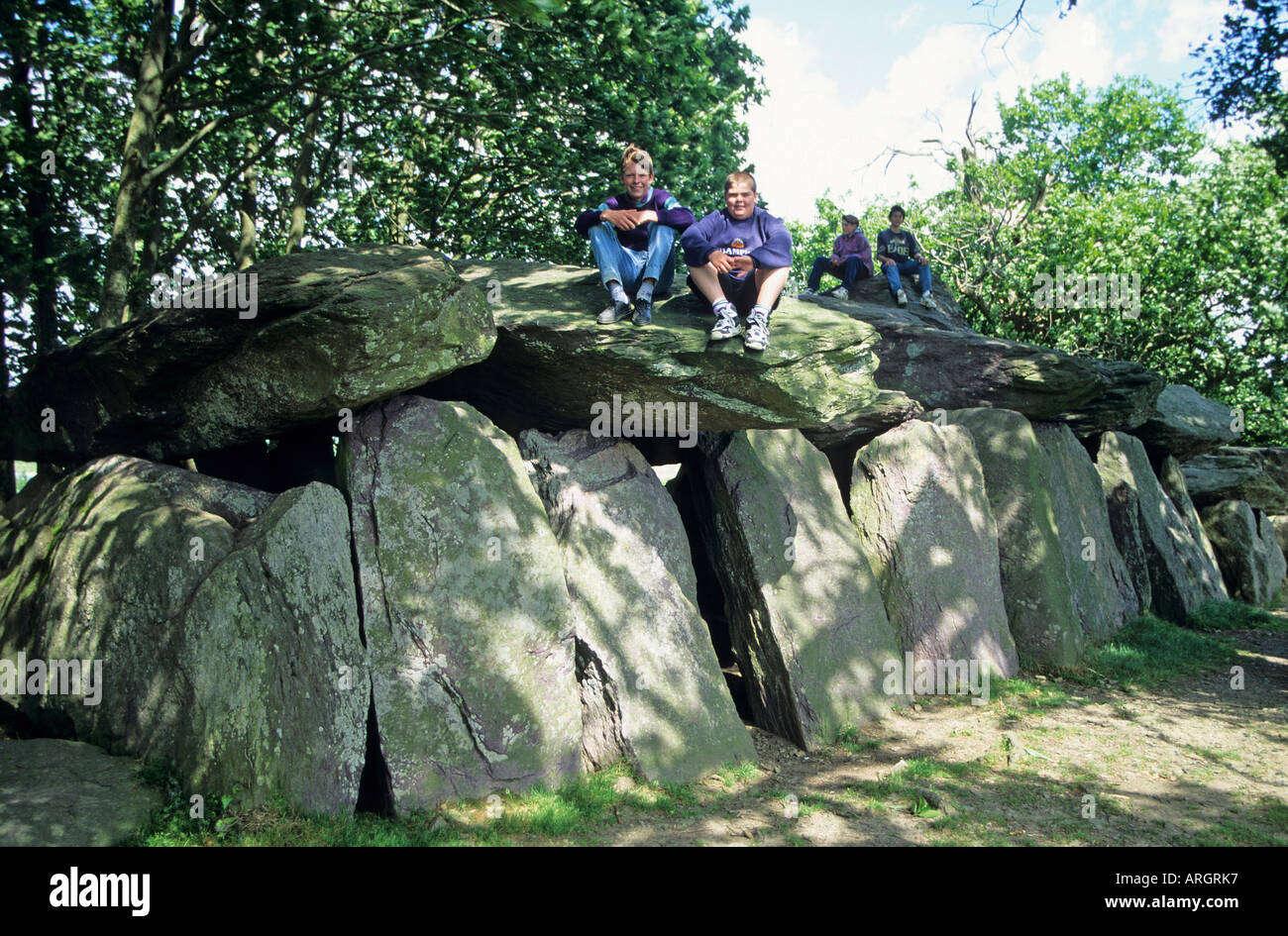 Les visiteurs assis au soleil sur le haut de la pierre posée sur le portique entrée de la Roche aux Fées comprenant 42 pierres de schiste pourpre massive l'un des plus beaux monuments mégalithiques de Bretagne Banque D'Images