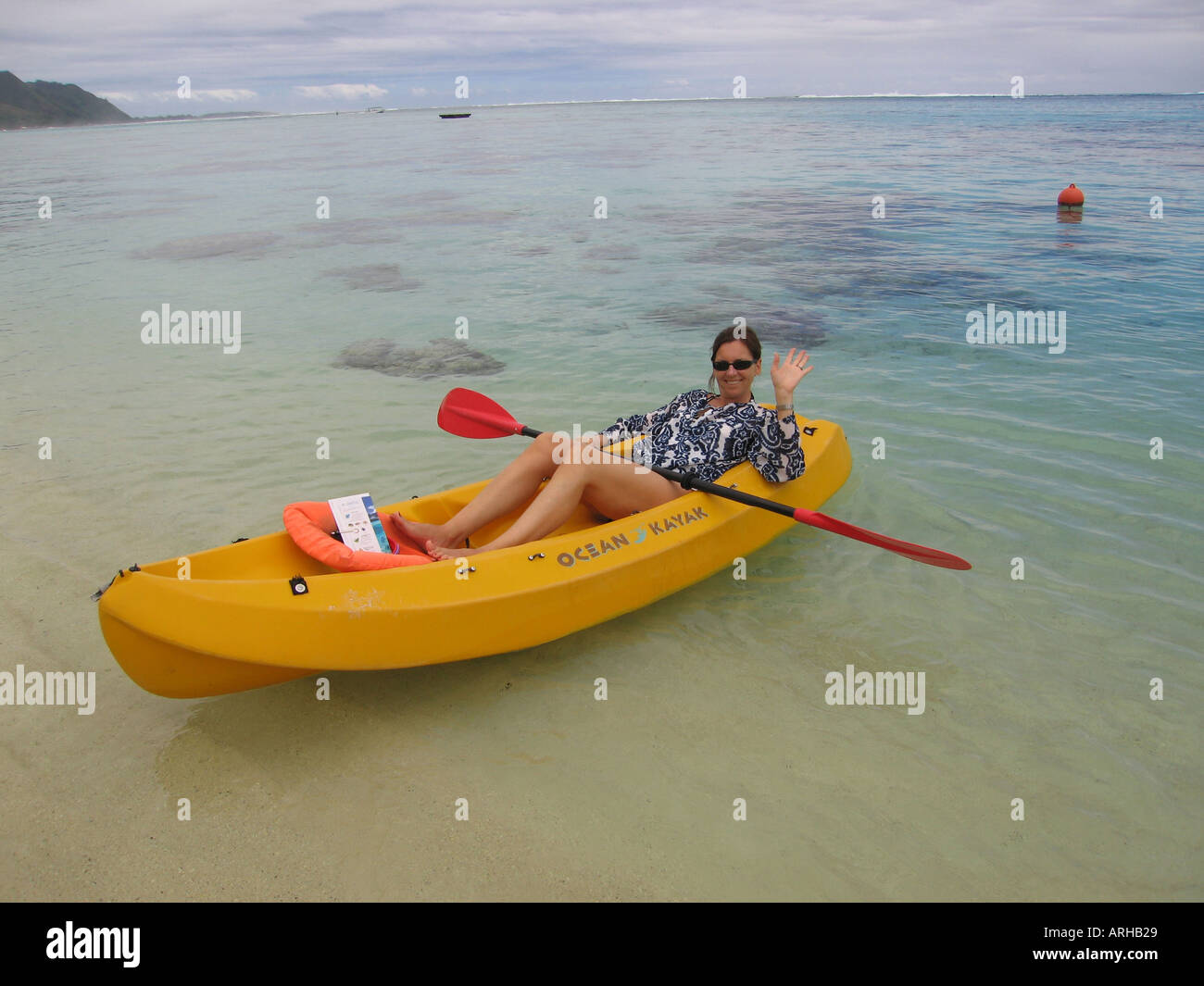 Une jeune femme couchée dans un bateau en eau peu profonde sur une plage Moorea Tahiti Polynésie Française du Pacifique Sud Banque D'Images