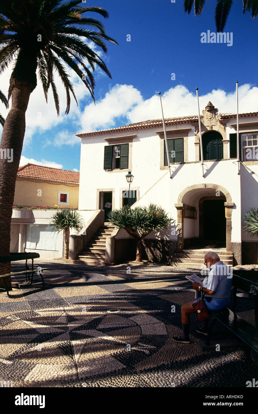 Un homme est assis lecture à l'ombre d'un palmier à côté de la Mairie sur Porto Santo Banque D'Images