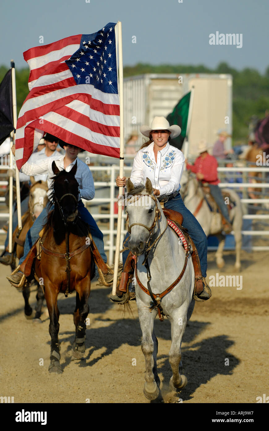 Cowgirl femme monte un taureau brama transportant drapeau dans la cérémonie précédant un rodéo Banque D'Images