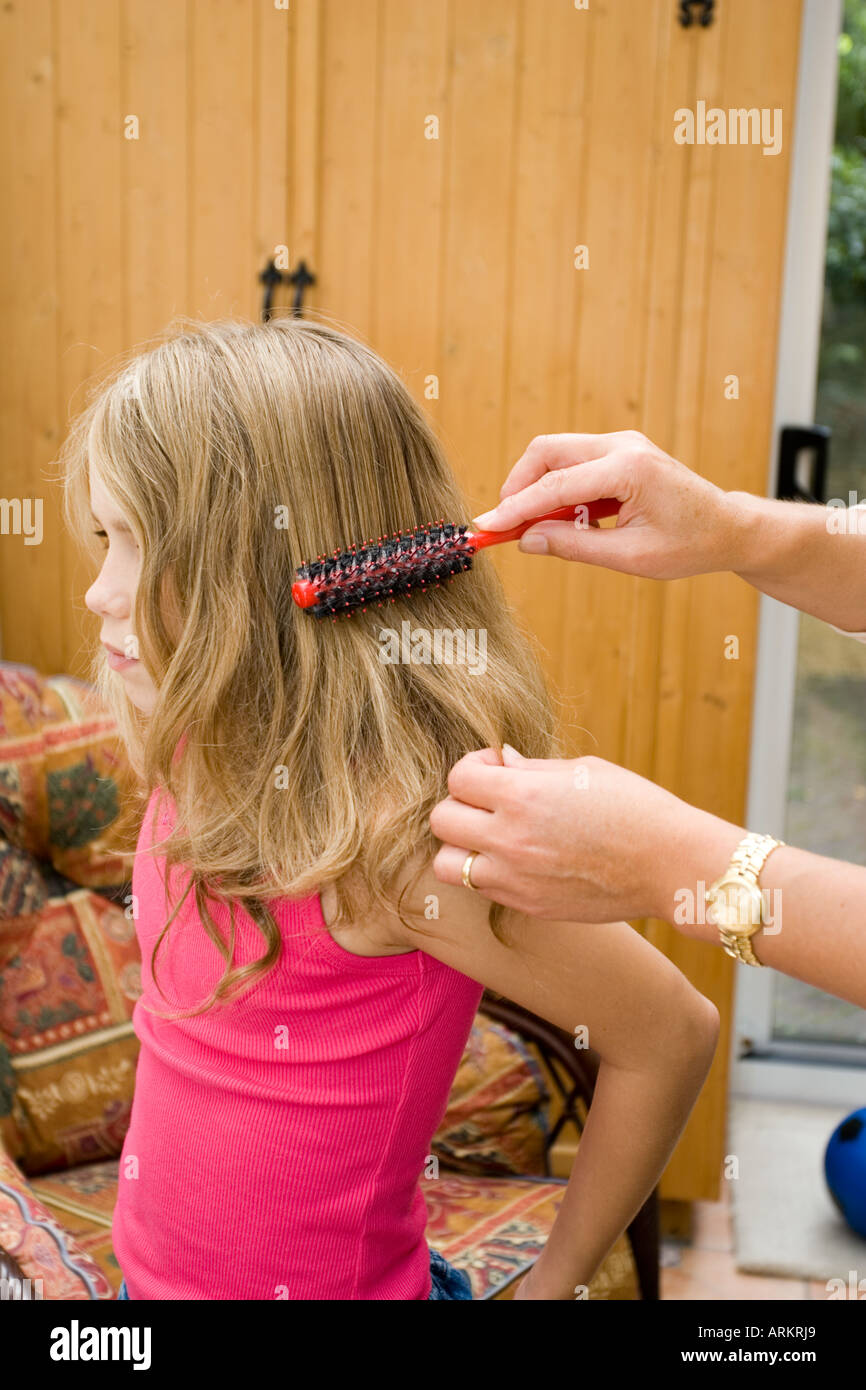 Brossage des cheveux emmêlés mère de neuf ans, fille, UK Banque D'Images