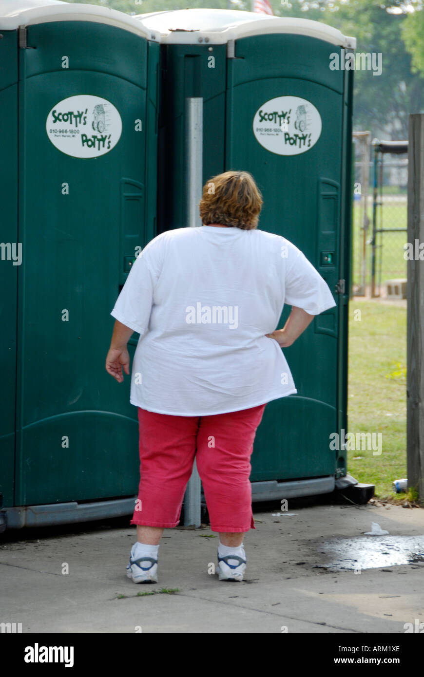 Grosses Femmes d'attente en ligne pour utiliser une salle de toilette portable Banque D'Images