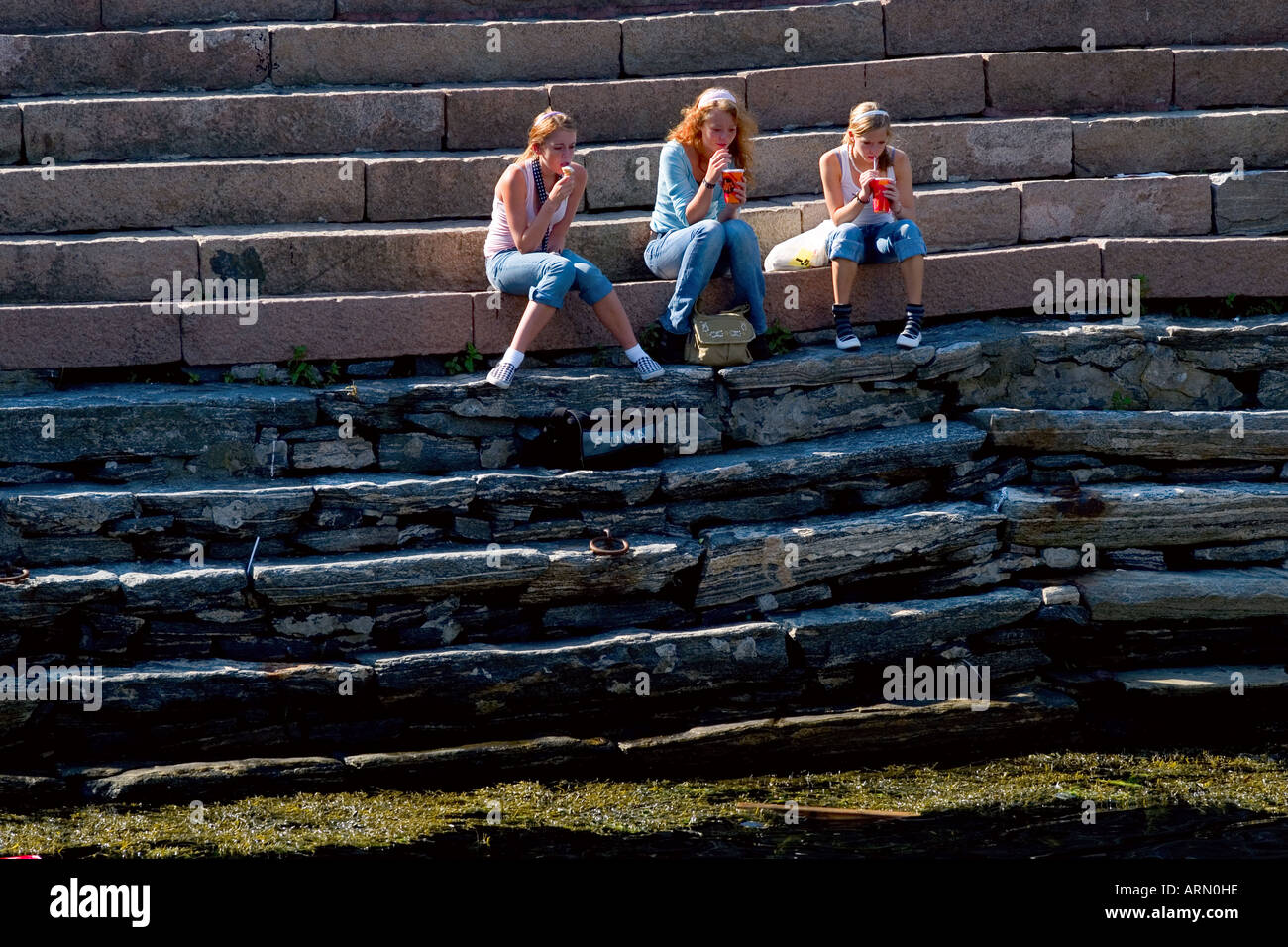 Trois jeunes filles se détendre près du canal à Alesund en Norvège Banque D'Images