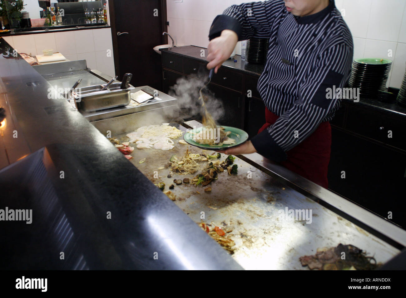 Chef chinois à la cuisson des aliments sur un gril chaud à La Corogne, Espagne Banque D'Images