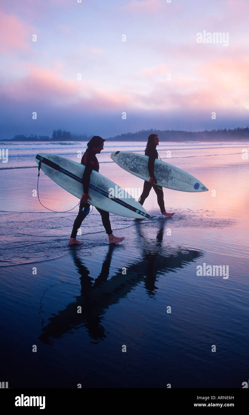 Deux jeunes surfeurs mâles marcher avec leurs conseils sur la plage, sur la côte du Pacifique, Longbeach, île de Vancouver, Colombie-Britannique, Canada Banque D'Images