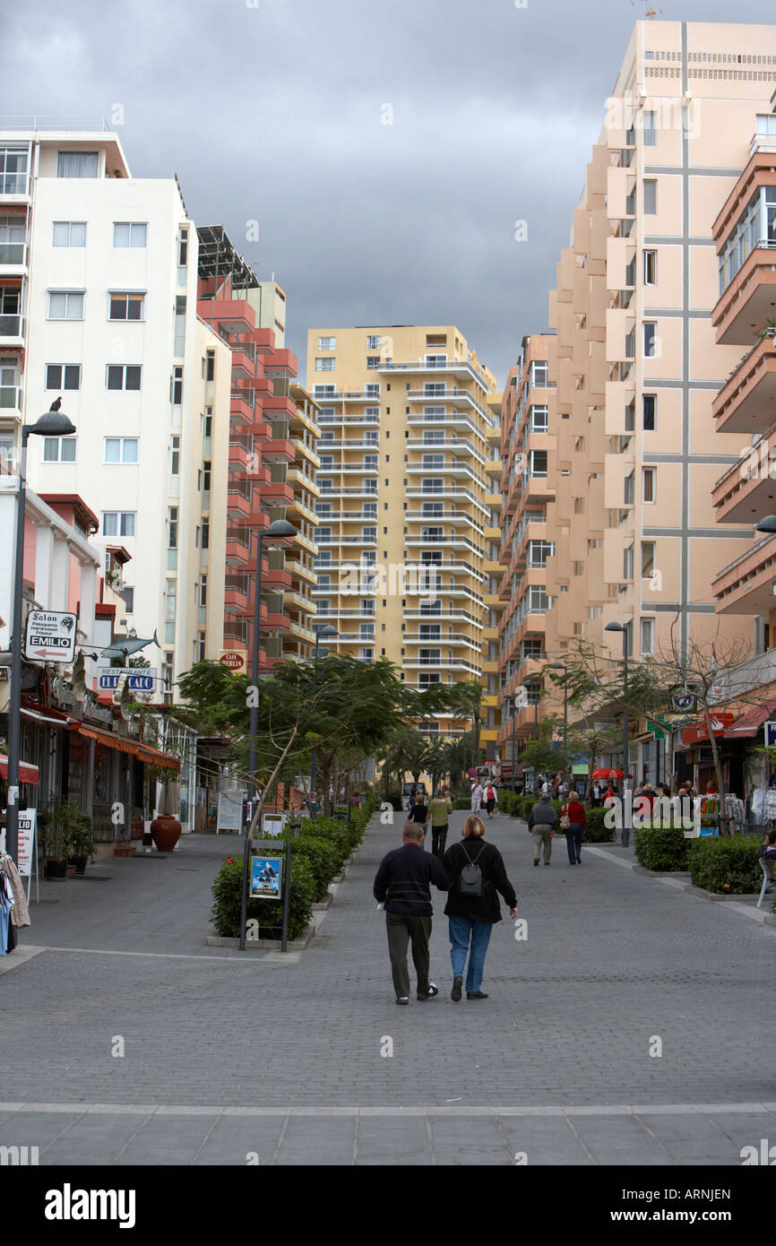 Les touristes à marcher le long rue bordée d'immeubles d'appartements et d'hébergement sur une rue dans la zone de villégiature Banque D'Images