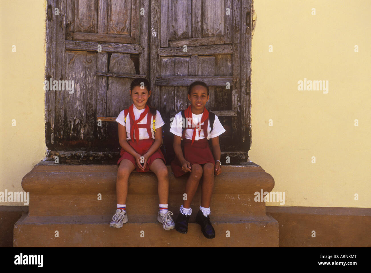 Cuba, Trinidad, deux filles de 10 ans, en uniforme d'asseoir sur des mesures pour chambre Banque D'Images
