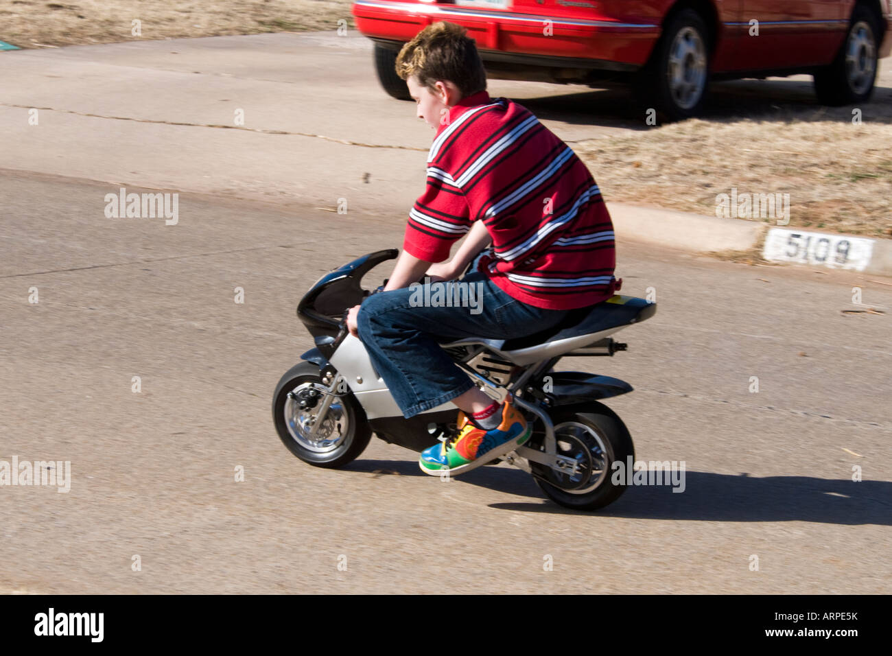 Un garçon de 13 ans jouit d'équitation son pocket bike dans son quartier. Banque D'Images
