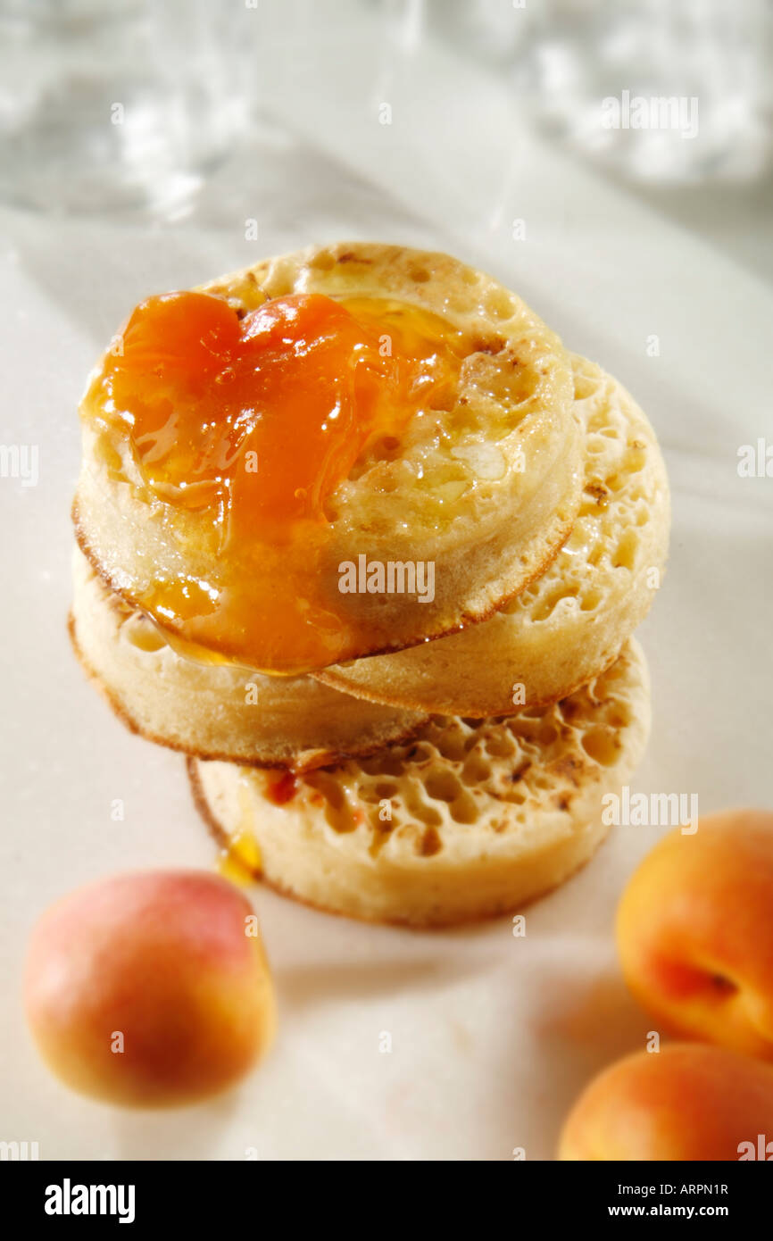 Close up de crumpets grillés au beurre avec confiture d'abricot prêt à manger dans un paramètre de table blanc Banque D'Images