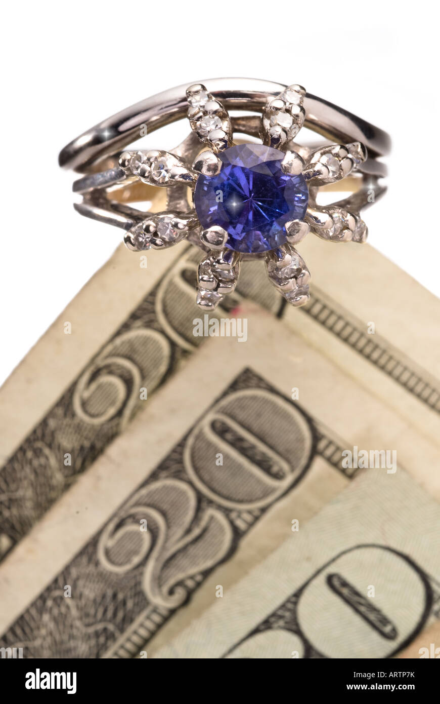 Un anneau de diamant repose au sommet d'une pile d'argent pour symboliser le coût élevé de bijoux Banque D'Images