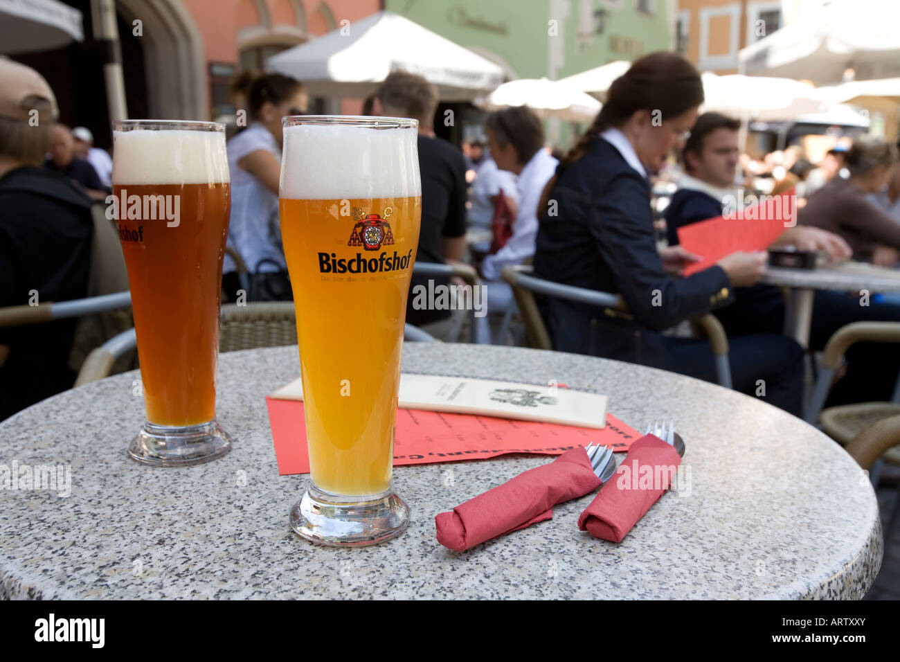 Verres de bière blonde légère et darl sur street cafe table avec diners derrière l'Allemagne Banque D'Images